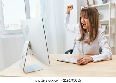 Angry evil blonde businesswoman screaming to desktop shaking fist at screen sitting at workplace in modern office. Irritated director work on computer online in financial corporation. Copy space
