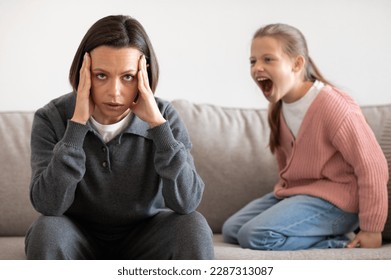 Angry excited aggressive teenager european girl yelling at sad tired millennial woman in living room interior. Relationship problems between mother and daughter, quarrel, hysteria - Shutterstock ID 2287313087