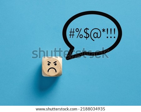 Angry face icon on a wooden cube with swearing or swearwords icons in a speech bubble. Swearing and bad language concept.