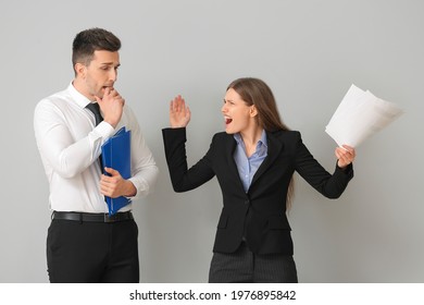 Angry Female Boss Scolding Her Male Secretary On Light Background