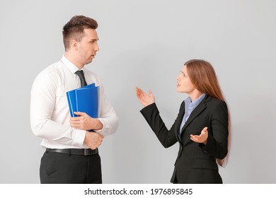 Angry Female Boss Scolding Her Male Secretary On Light Background