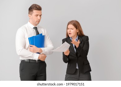 Angry Female Boss Scolding Her Male Secretary On Light Background