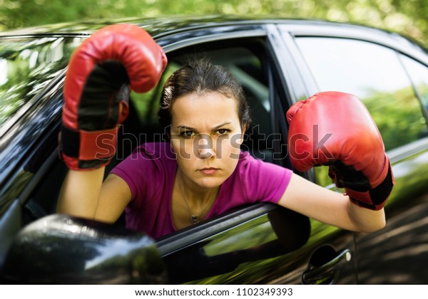Angry female driver is wearing box gloves,standing\
inside the car.