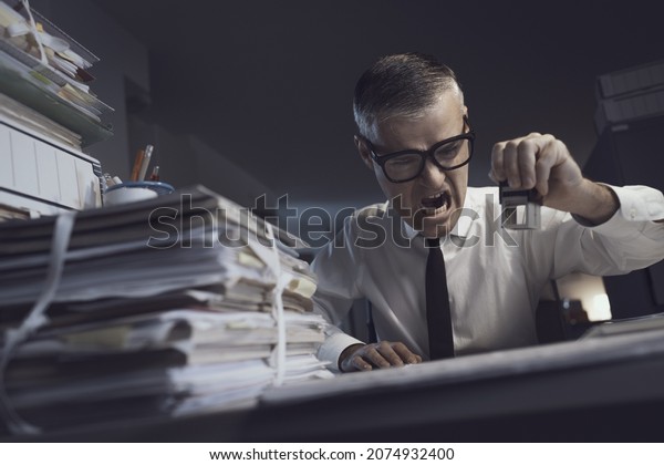 Angry frustrated office clerk doing a repetitive\
job in his office