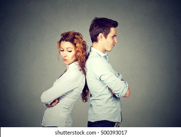 Angry frustrated young couple standing back to back. Side profile unhappy sad man and woman. Negative emotion face expression reaction