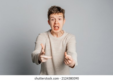 Angry Furious Teenager Boy Wearing Casual Clothes Pointing Displeased And Frustrated To The Camera, Standing Over Gray Background