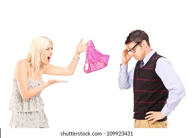 Angry girlfriend shouting at her boyfriend and holding female knickers isolated on white background