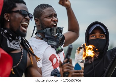 Angry Group Of Black People In Gas Mask Riot, Set Fire To Bottles With Cloth. Emotional Black-skinned Men Can't Sit At Home When Injustice Is Everywhere