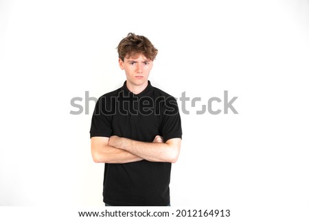 Angry guy looking at camera with his arms crossed. portrait, white background, 18-20 years old. White european guy.