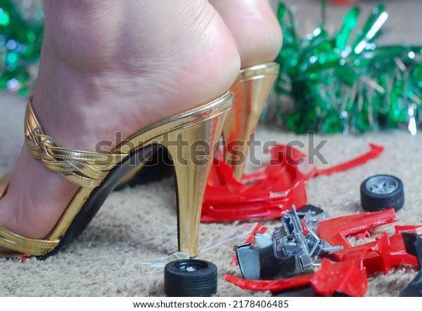 An angry housewife or mother, has stomped on and\
crushed a toy car in her sexy high heels to teach a lesson about\
being untidy (Close Up)