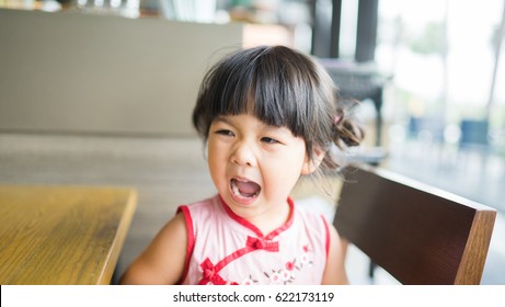 Angry And Hungry Little Asian Girl Is Screaming In Restaurant.angry Kid.Facial Expression.