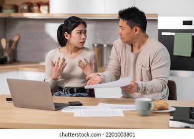 Angry Husband Shouting At His Wife, Sad Asian Couple Sitting At Kitchen Table In Front Of Laptop, Holding Papers, Checking Monthly Spendings, Man Scolding Woman For Wasting Money From Family Budget