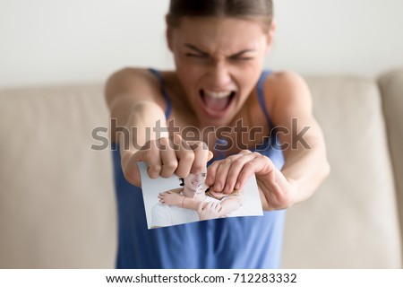 Angry hysterical woman tearing photo of happy couple, erasing memories of ex-boyfriend after breaking up divorce, frustrated lovelorn teenager feeling heartbroken ripping picture of past relationship