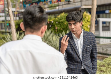 An angry indian man has a heated argument with another asian guy. Workmates having a disagreement while outside the office. - Shutterstock ID 2311342463