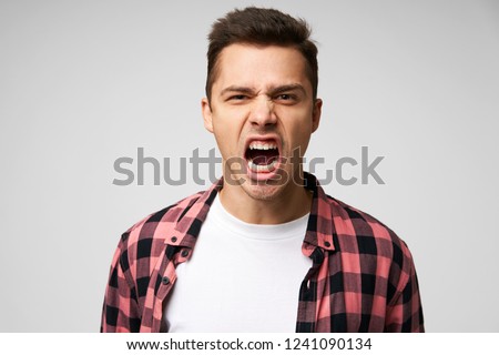 Angry, irate man with grumpy grimace on his face,with mouth opened in shout, ready to argue and swear, wants to gain respect, show strength, isolated over white background