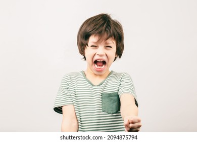 Angry Kid Shouting And Rising His Fist. Aggressive Little Boy With Mouth Wide Open Looking To The Camera. ADHD Syndrome