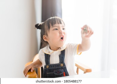 Angry Kid.Little Asian Girl Looking At Her Mother And Fighting With Her Mom.Furious Toddler Kid Got Upset.she Has A Negative Attitude.Depressed Little Girl Complaining.Kid Play Toy At Home.