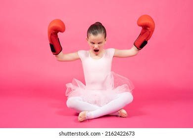 Angry Little Ballet Dancer Wearing Boxing Gloves Showing Bideps And Looking At Camera Isolated On Pink Background. Female Stereotypes Concept.