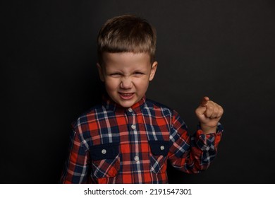 Angry Little Boy On Black Background. Aggressive Behavior