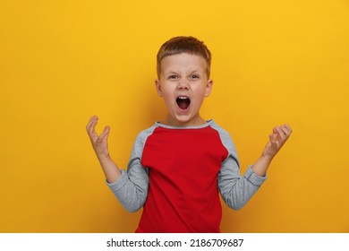 Angry Little Boy Screaming On Yellow Background. Aggressive Behavior
