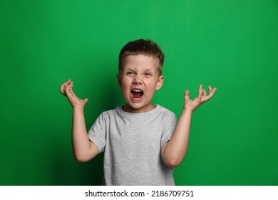 Angry Little Boy Screaming On Green Background. Aggressive Behavior