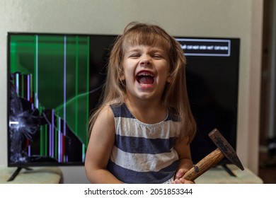 angry little girl deliberately smashed the TV with a hammer and is happy. uncontrollable child with conduct disorders