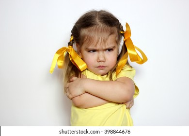 Angry little girl with yellow bows and yellow T-shirt over white background, sign and gesture concept - Shutterstock ID 398844676