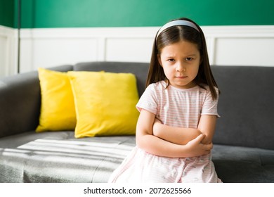 Angry little kid with bad temper feeling annoyed after disobeying her parents. Upset 5 year old girl looking at the camera 