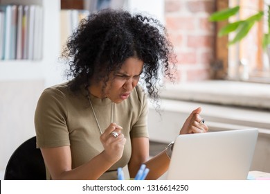 Angry mad african businesswoman feeling crazy furious outraged hates not working stuck laptop online problem, stressed annoyed black woman frustrated about computer failure or data loss at work