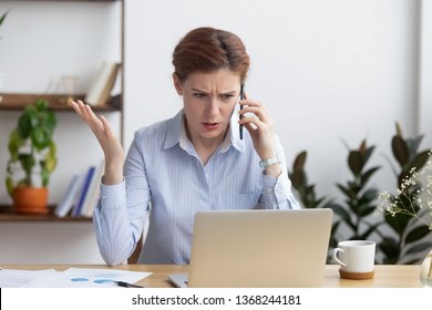 Angry mad businesswoman talking on phone looking at laptop, annoyed stressed office worker arguing with client by mobile solving online computer business problem with technical customer support