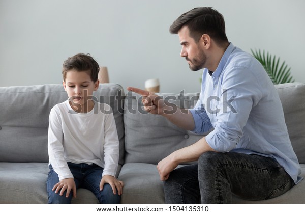 Angry mad father scolding lecturing sad preschool\
kid son for bad behavior at home, serious parent dad punish little\
upset guilty child boy pointing finger demand discipline, family\
conflicts concept