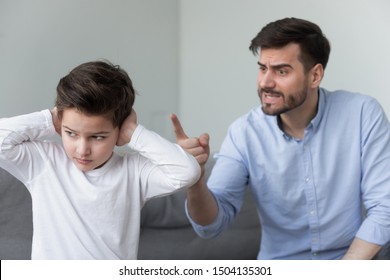 Angry mad father shouting at stubborn fussy little kid son close ears not listening ignoring dad punish rebellious kid boy for bad behavior, parents and children family conflicts arguments concept
