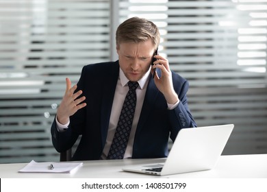 Angry mad frustrated businessman talking on phone complaining on bad service solving business corporate problem, annoyed stressed boss manager make call arguing by mobile telephone sit at office desk