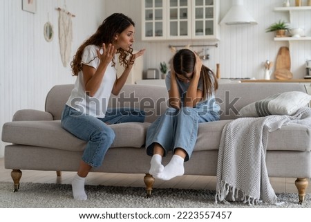 Angry mad mother trying to discipline child, expressing frustration shouting at teenage daughter sitting on sofa covering ears with hands. Psychological effects of yelling at kids, verbal abuse