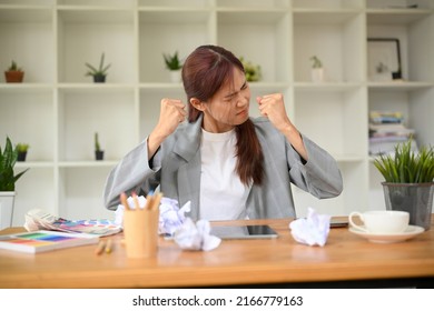 Angry mad pissed off young asian businesswoman unsatisfied with her work project, crumpling a document paper at her office desk. Overworked, Failure