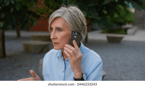 Angry mad senior businesswoman Caucasian old woman stressed female argue talking mobile phone dissatisfied mature business lady on city street talk smartphone conflict irritated shout quarrel outdoors - Powered by Shutterstock