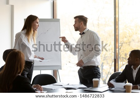 Angry male and female colleagues argue over paperwork at corporate team meeting, annoyed coworkers rivals man woman disputing about documents in office, gender rivalry, conflicts at work concept