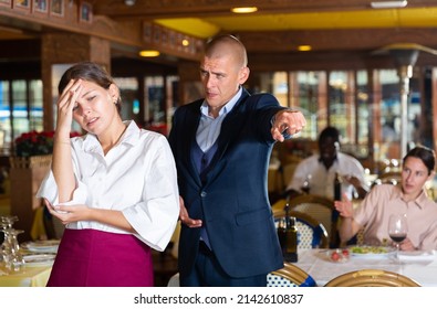 Angry man client of restaurant yelling at young waitress chasing her away