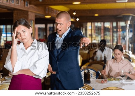Angry man client of restaurant yelling at young waitress chasing her away