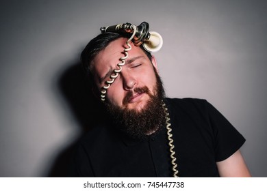 Angry Man With Closed Eyes Wrapped The Cord From The Phone On A Dark Background