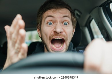 Angry Man Driving A Car. Male Driver Gesturing And Shouting Behind The Wheel Of The Car.