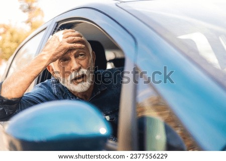 Angry man driving a car. The old men with an expression of displeasure is actively gesticulating behind the wheel of the car. Angry business man in a car.
