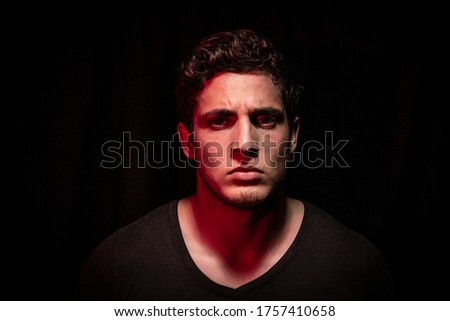 Angry man expressing abhorrence in dark backround. dramatic lights