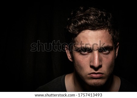 Angry man expressing abhorrence in dark backround. dramatic lights