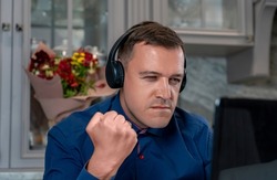 Angry Man With Headphones Clenched His Fist, Looking At Laptop Screen, Writes Offensive Comments To Haters, Spreads Fake Rumors, Feeds Trolls Online. Concept Hate, Trolling, Anger On Internet Forum