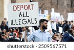 Angry man hold deport all illegals banner. Immigration crisis protest. Crowd wave placard. Stop no immigrants deportation. Anti migration demonstration. Guy against migrants. Refugee march city street