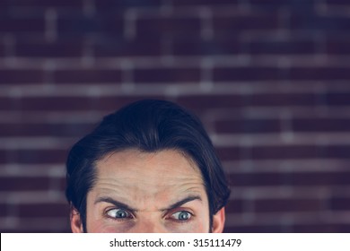 Angry Man With Raised Eyebrows Looking Away Against Brick Wall