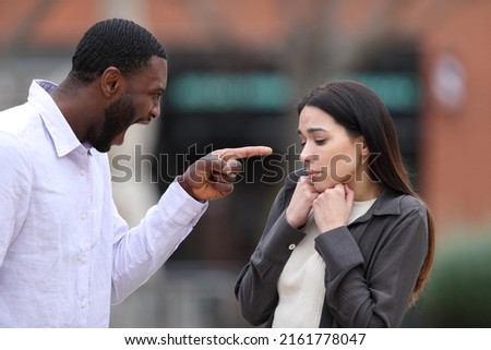 Angry man scolding and accusing to a scared woman in the street