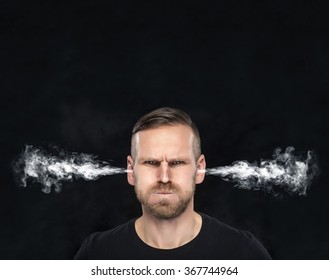 Angry man with smoke or fume coming out from his ears on dark background.