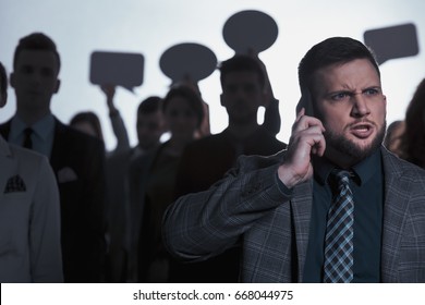 Angry Man Talking On Phone, Crowd In Background